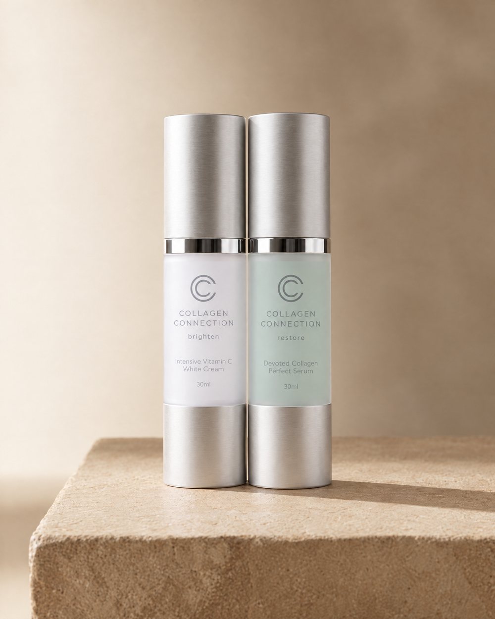 Collagen Serum and Vitamin C Cream, the two 30 ml bottles together on travertine stone