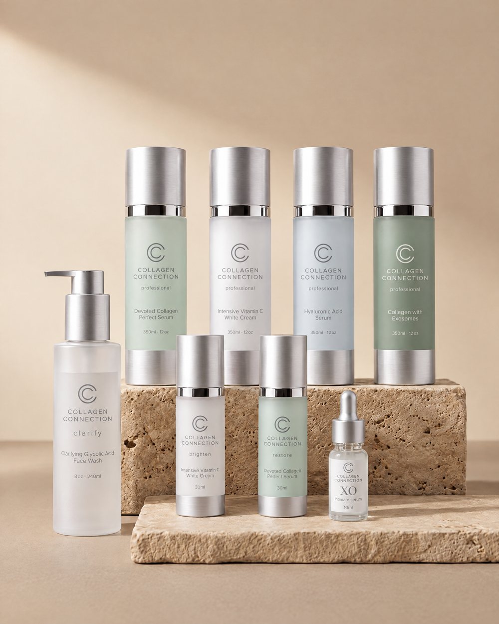 The full Collagen Connection range on travertine stone: four professional back bar bottles, the collagen serum, the Vitamin C cream, the glycolic face wash and the XO intimate serum