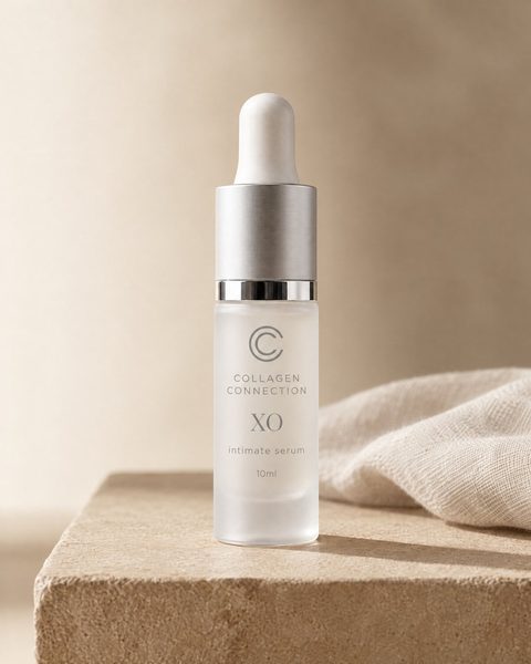 XO intimate serum, 10 ml glass vial with a silver dropper beside folded linen